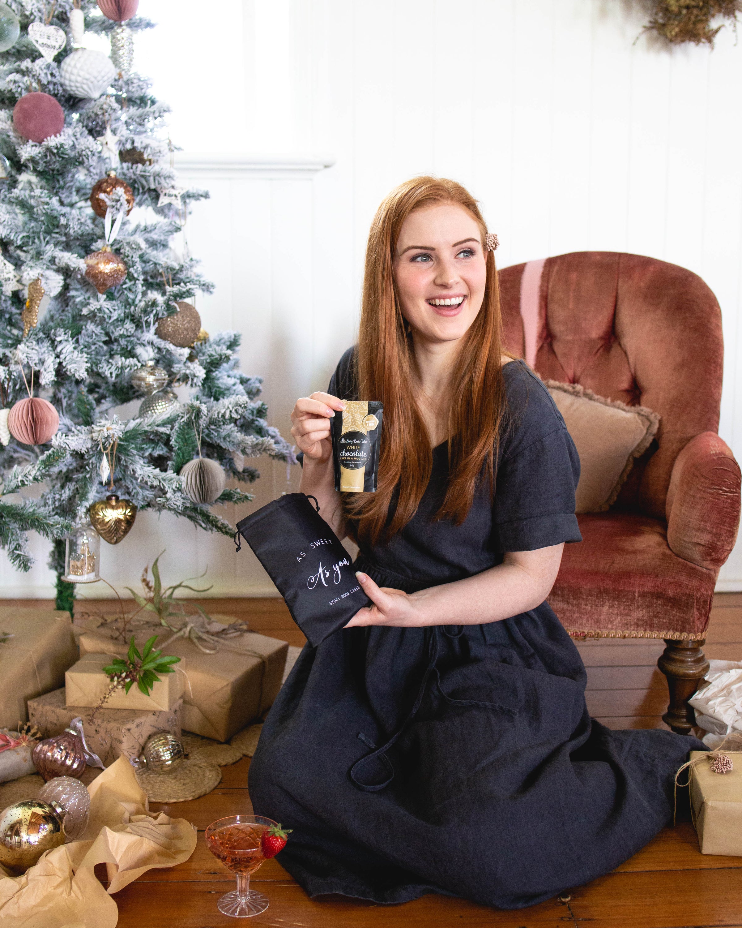 Woman holding a product in front of a Christmas tree and chair